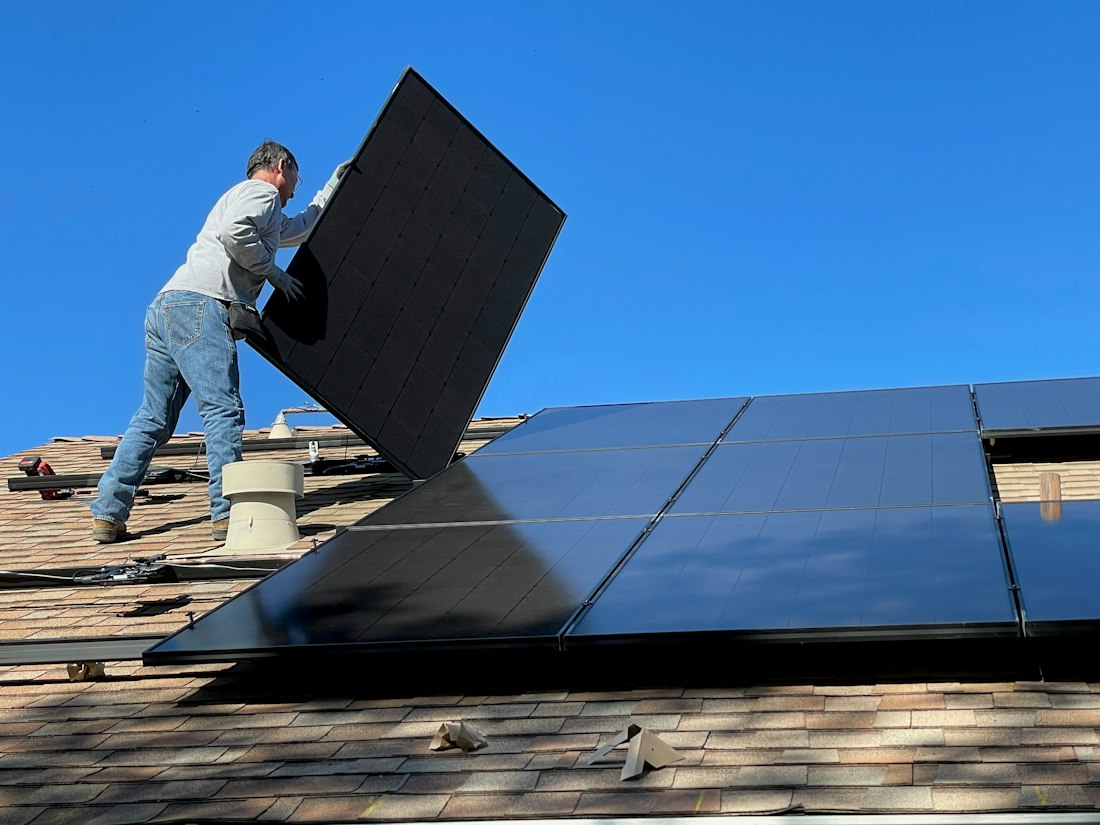 Technician installing solar panels on a roof